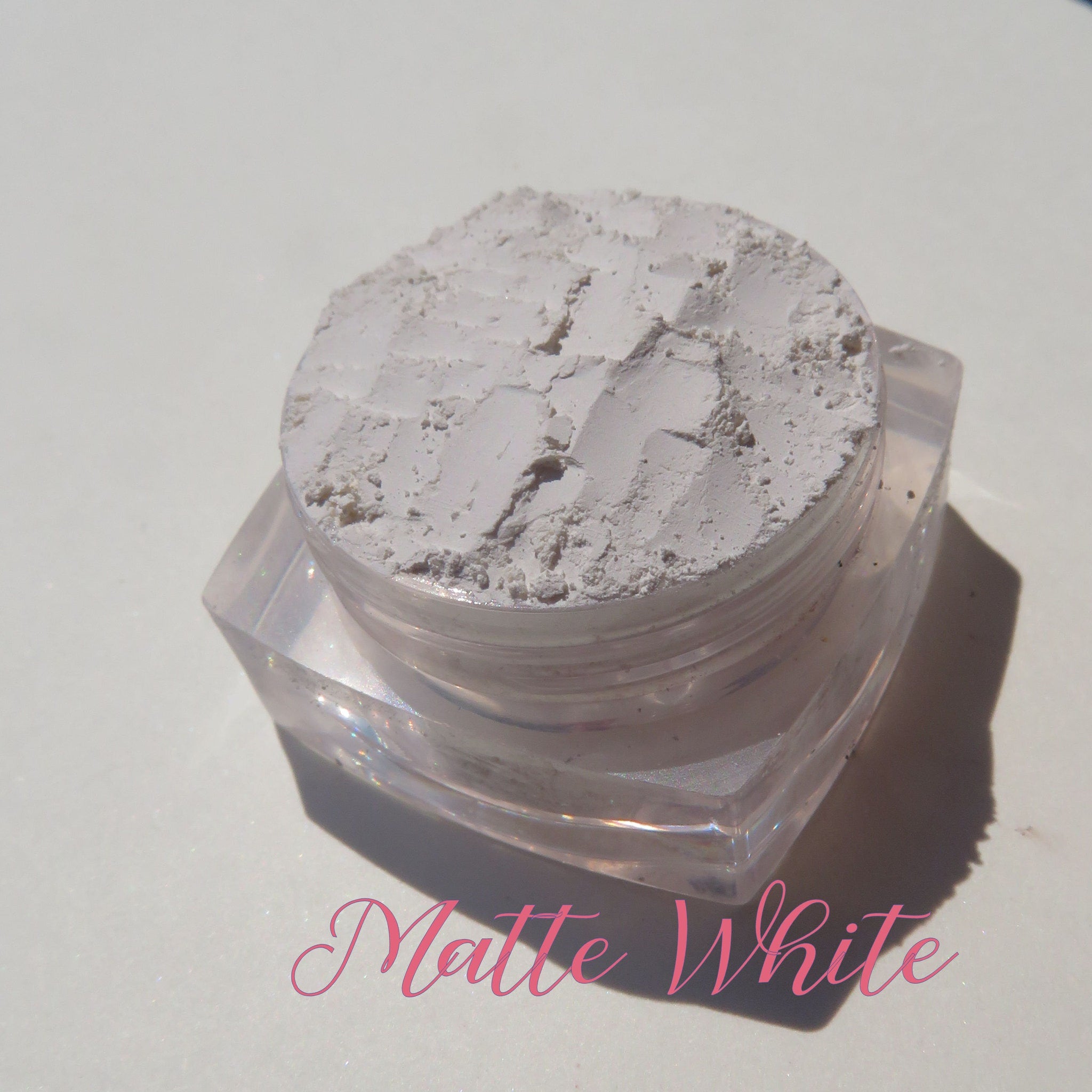 Close-up of matte black and white vegan eyeshadow pans with smooth mineral texture in sleek compact