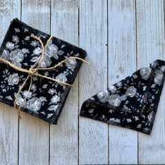 Reusable cloth napkins with black floral pattern and black stitched edges, tied with twine