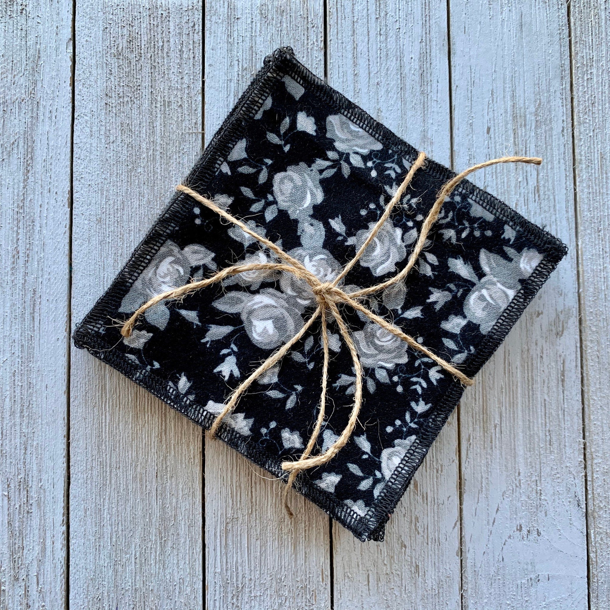 Coasters black floral fabric with gray roses tied with twine on wood background