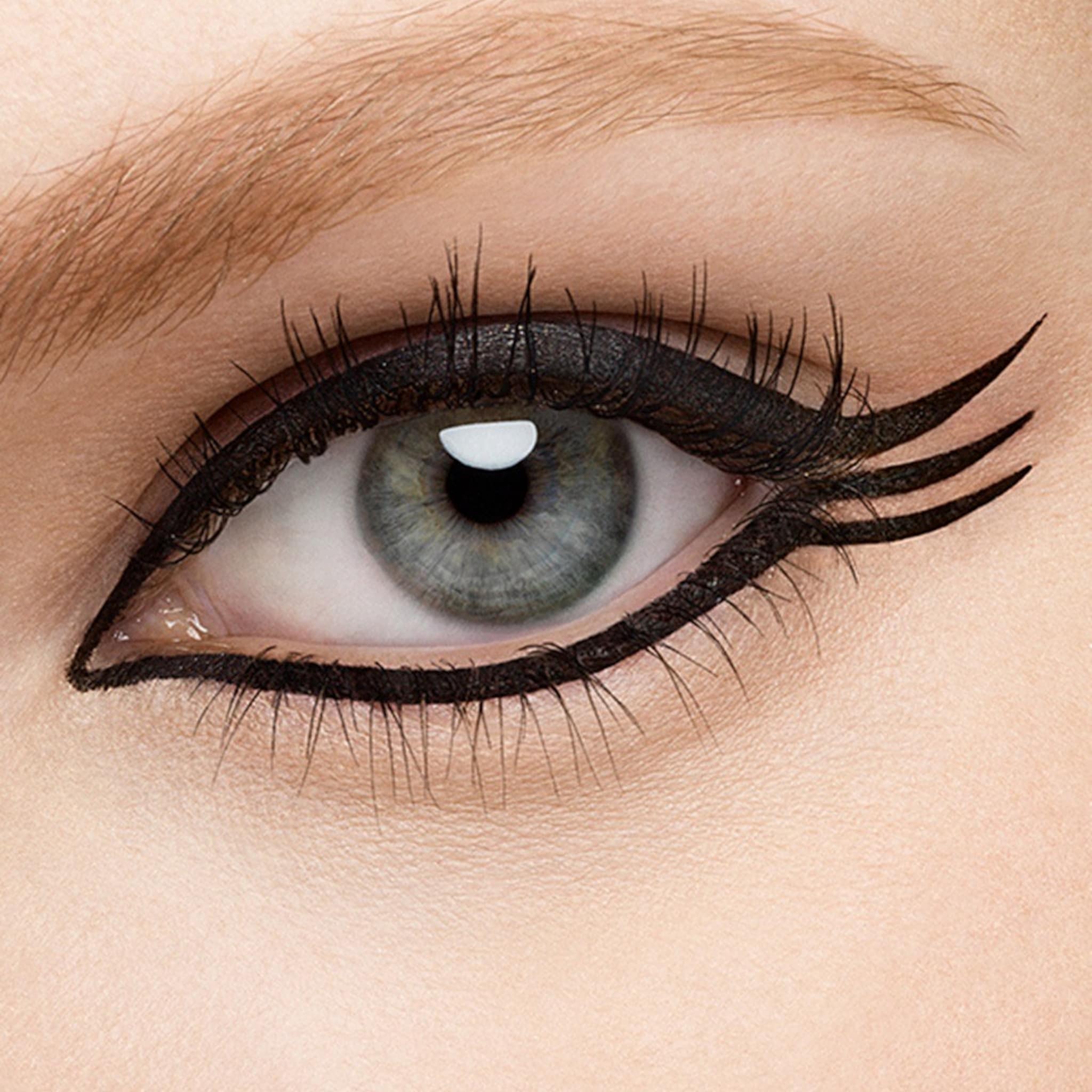 Eyeliner application with black liquid, winged style on eye, close-up view