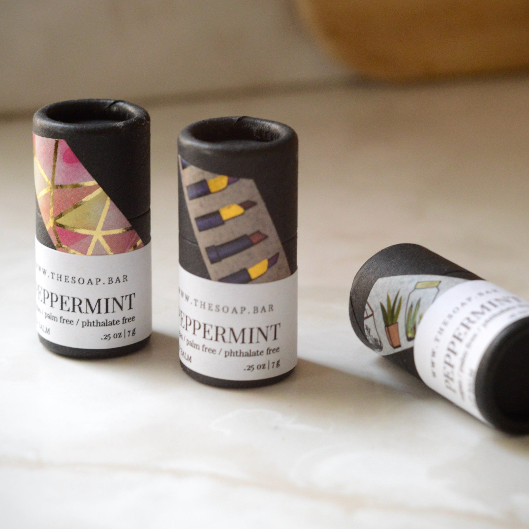 Peppermint balm tubes, black cardboard, patterned labels, "The Soap Bar" branding visible