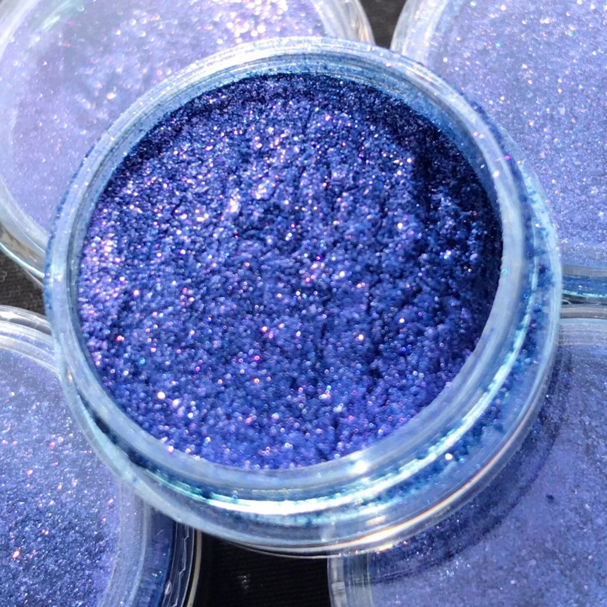 Close-up of shimmery eyeshadow pigment showing vibrant color payoff and fine glitter particles