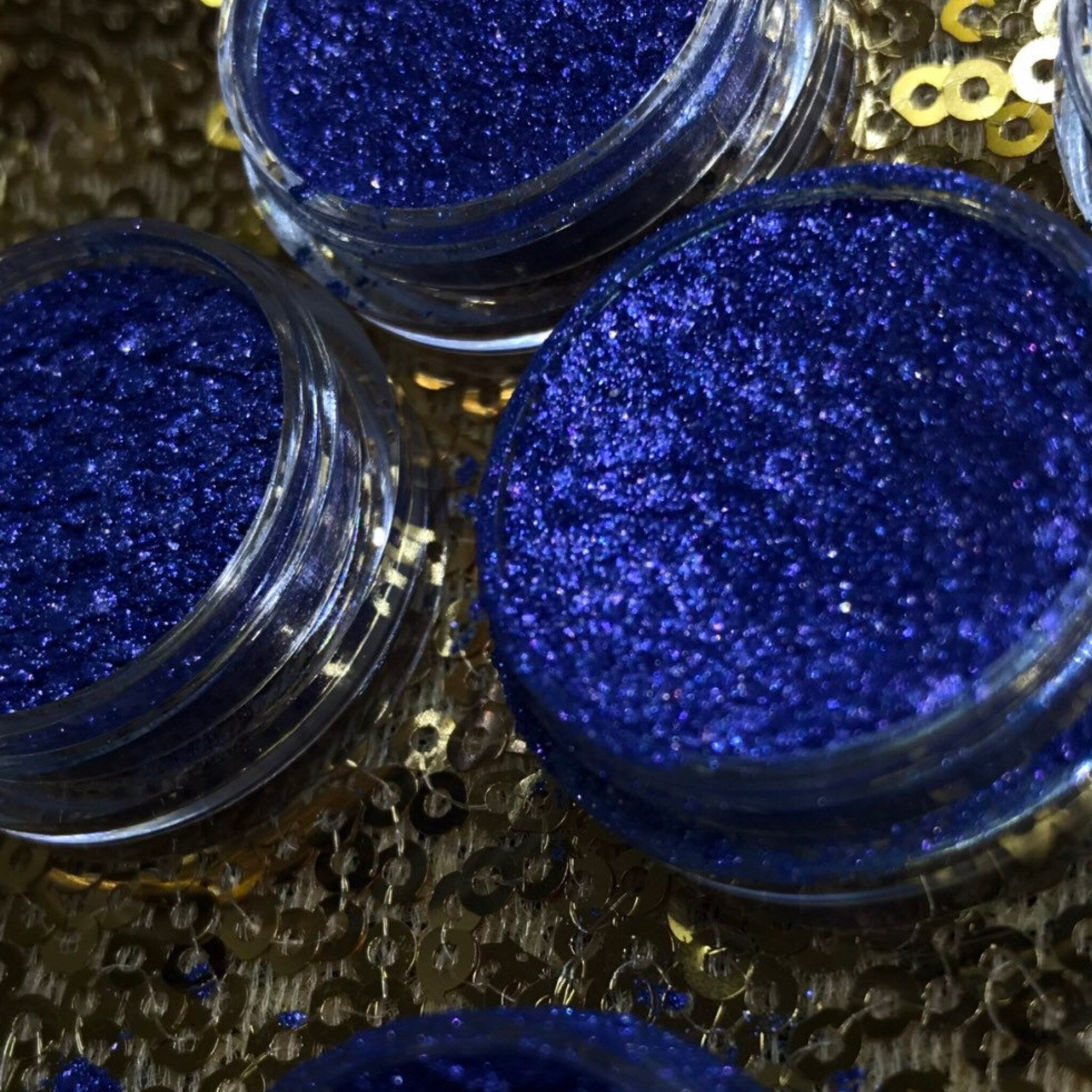 Side view of shimmery single eyeshadow pigment pot showing metallic finish and compact size