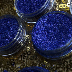 Side view of shimmery single eyeshadow pigment pot showing metallic finish and compact size