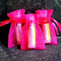 Lip balm tubes in pink mesh bags with red ribbon ties, "MOTHERPUCKER" text visible