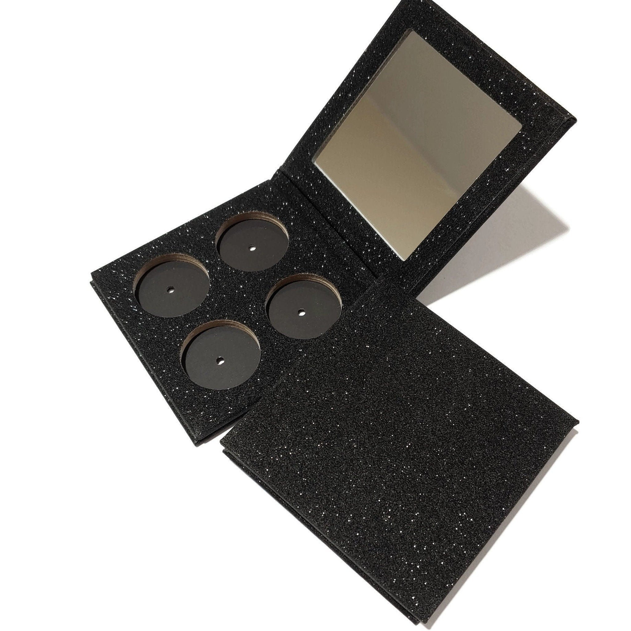 Makeup palette with black glitter material and mirror, open to reveal empty wells