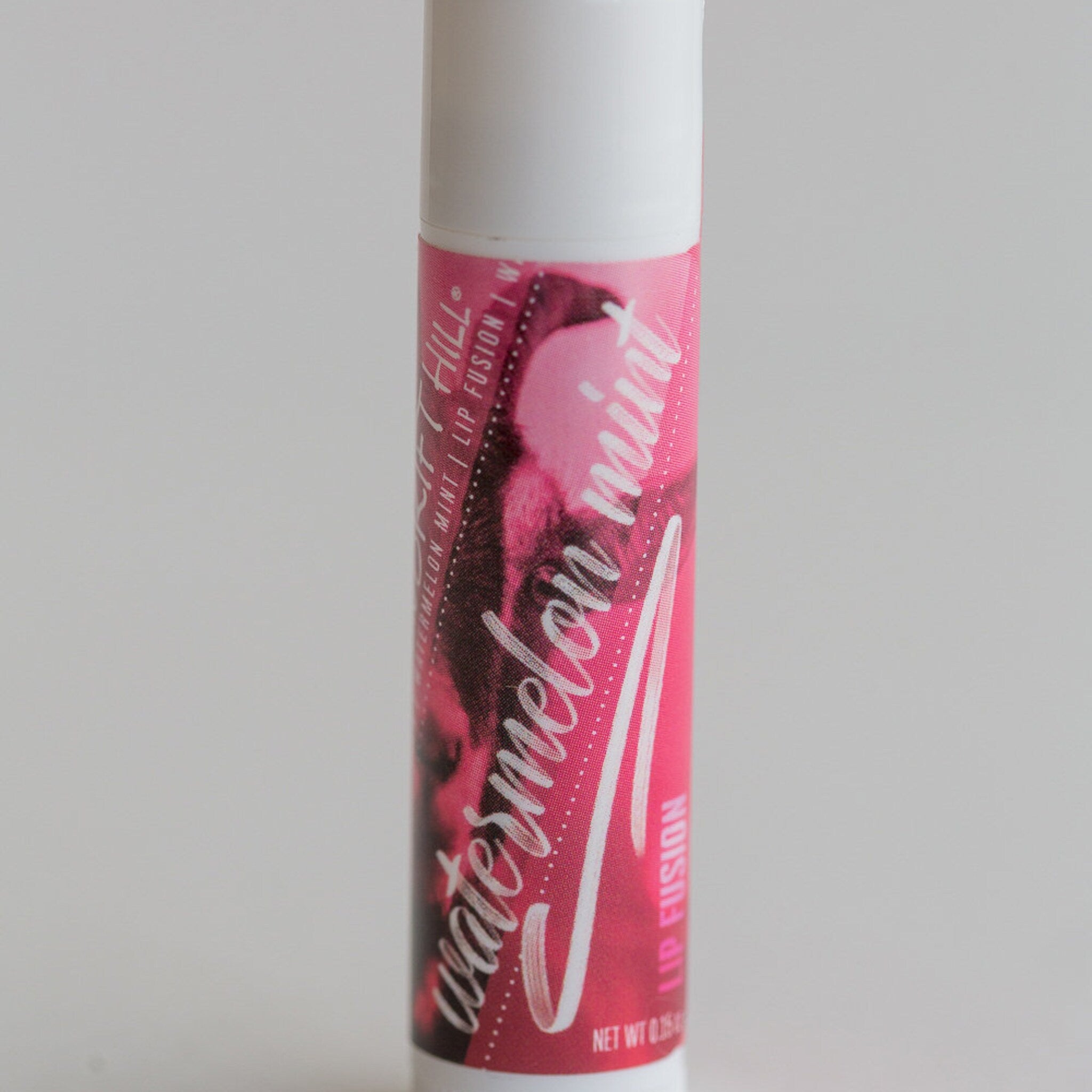 Lip balm tube with white and pink label, watermelon mint text, and Hill brand name