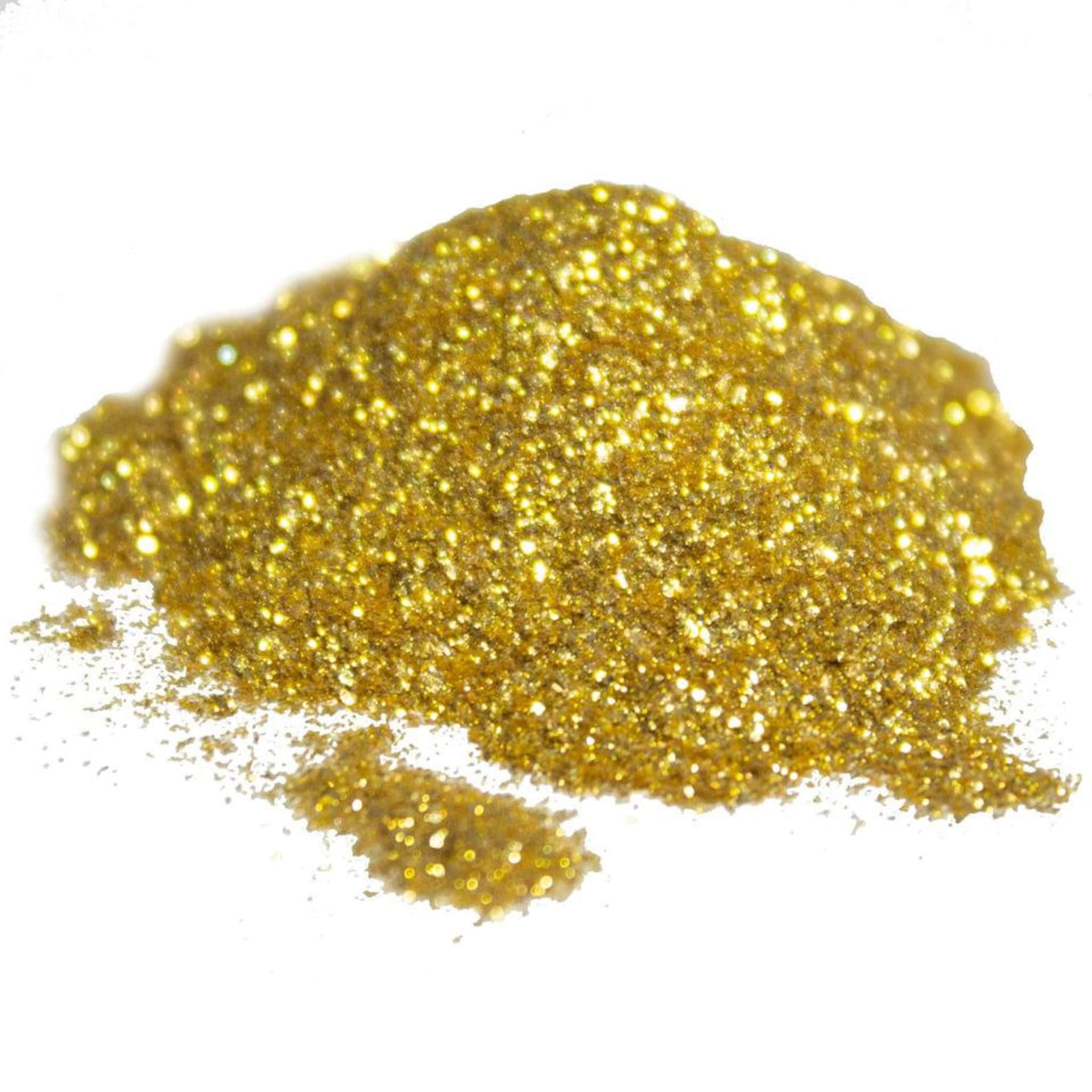 Gold glitter pigment powder spilled on marble surface with brush and makeup palette