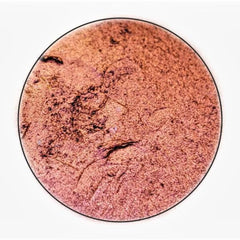 Close-up of fingertips applying shimmery orange-to-pink multichrome eyeshadow to eyelid crease