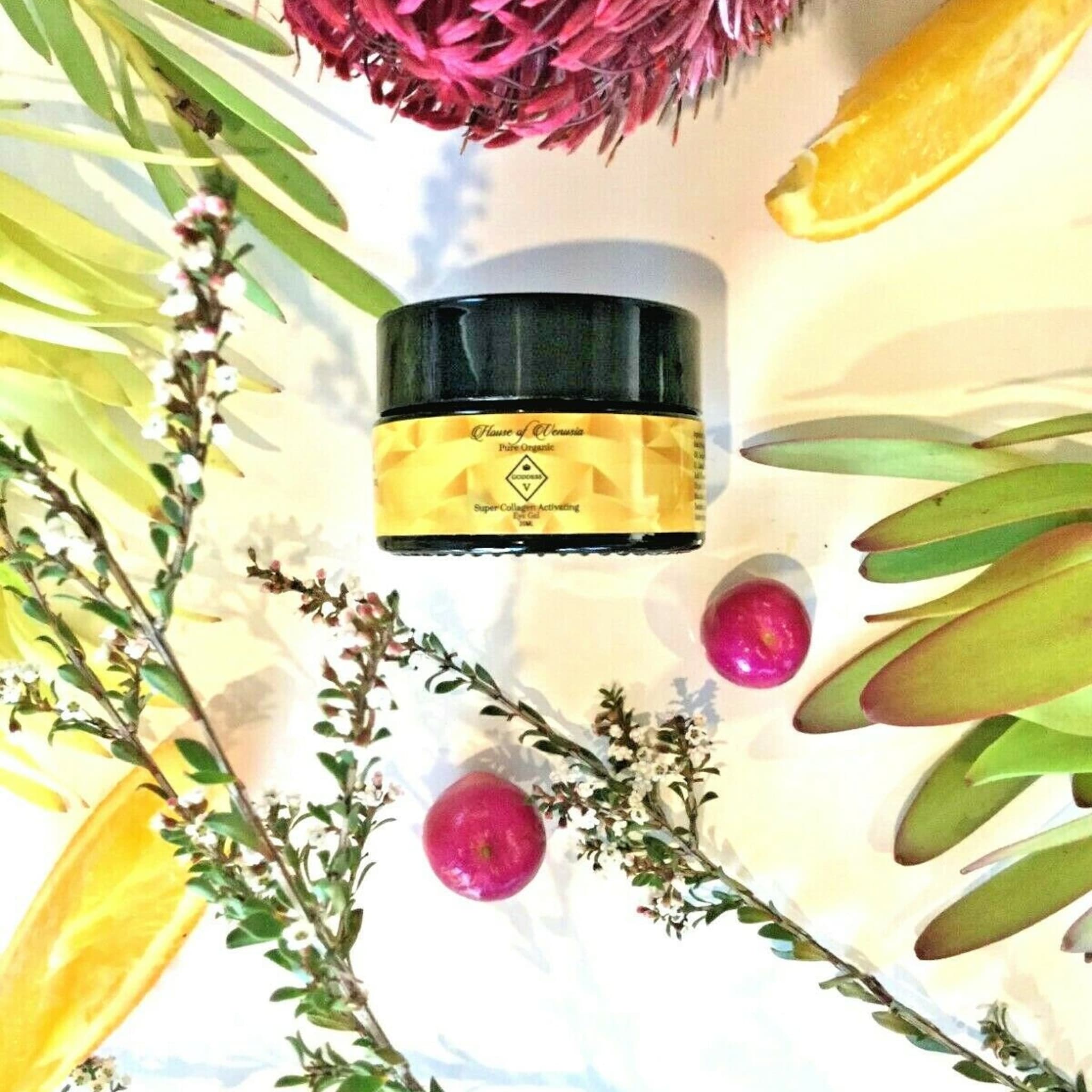 Black jar with yellow label, text "House of Venusia" and floral arrangement around it