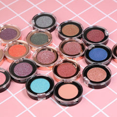 Close-up of shimmering bronze eye shadow palette with mirrored compact and dual-ended applicator brush
