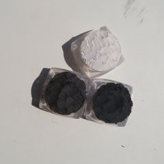 Side view of matte vegan eyeshadow set showing dark shades palette, black eyeliner, and loose powders in sleek black packaging