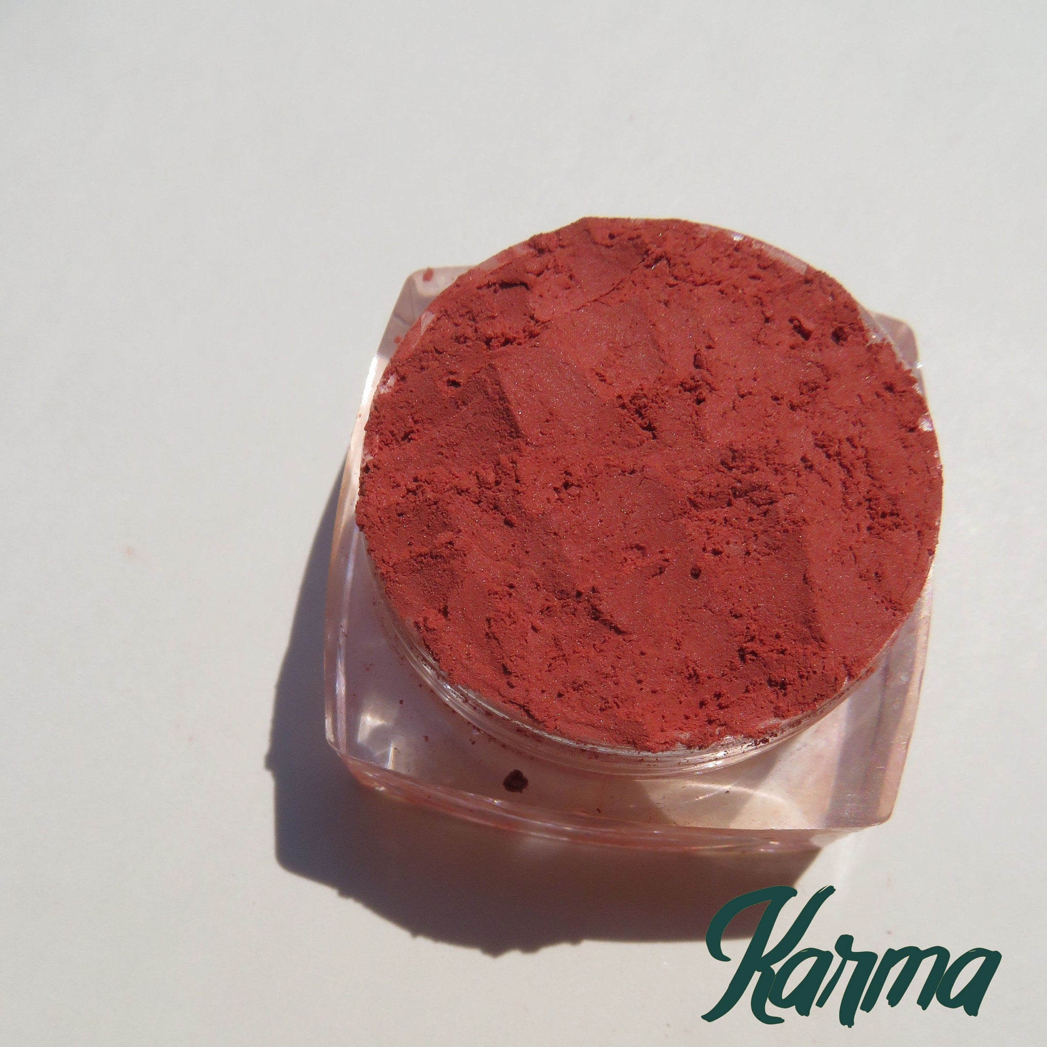 Vegan matte loose mineral eyeshadow in vibrant orange-red shade with smooth powder texture in a small sifter jar
