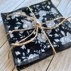 Makeup remover cloths, black floral pattern, tied with twine, on wood surface