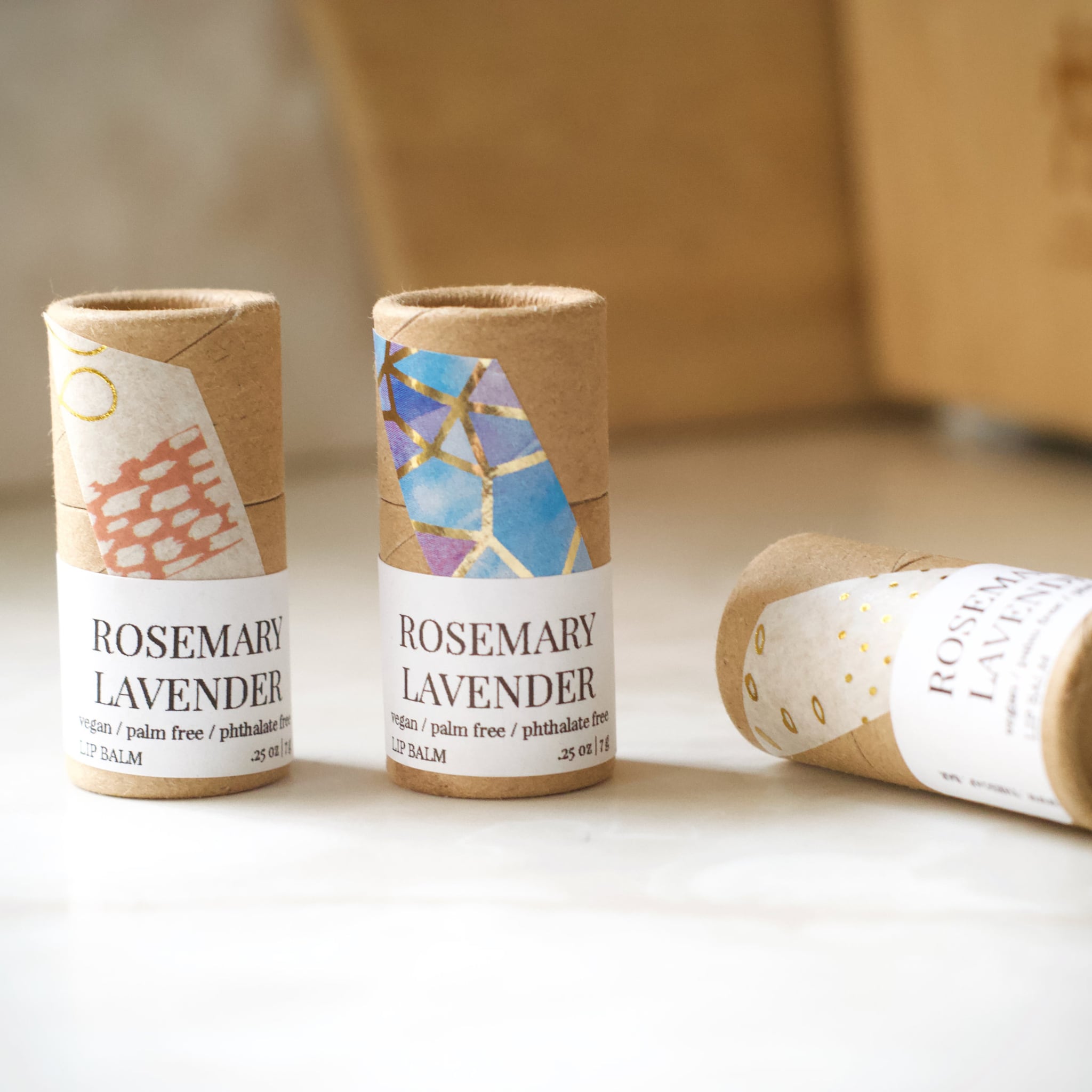 Lip balm tubes with brown paper, patterned tape, and white labels with text