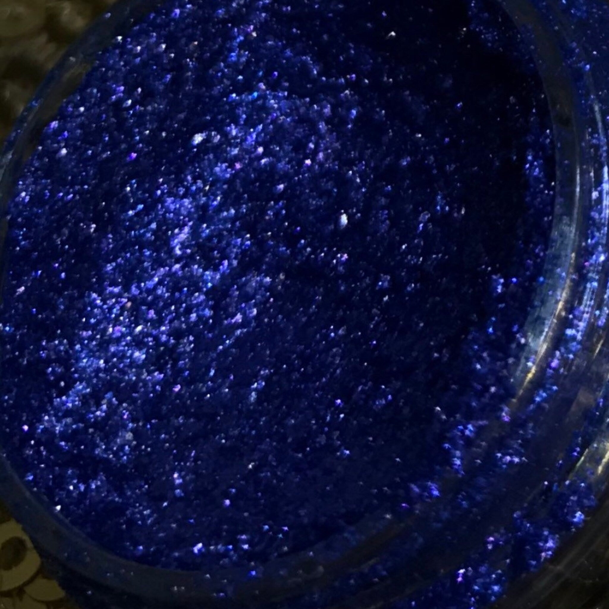 Close-up swatch of shimmery eyeshadow pigment showing vibrant color payoff and fine glitter particles