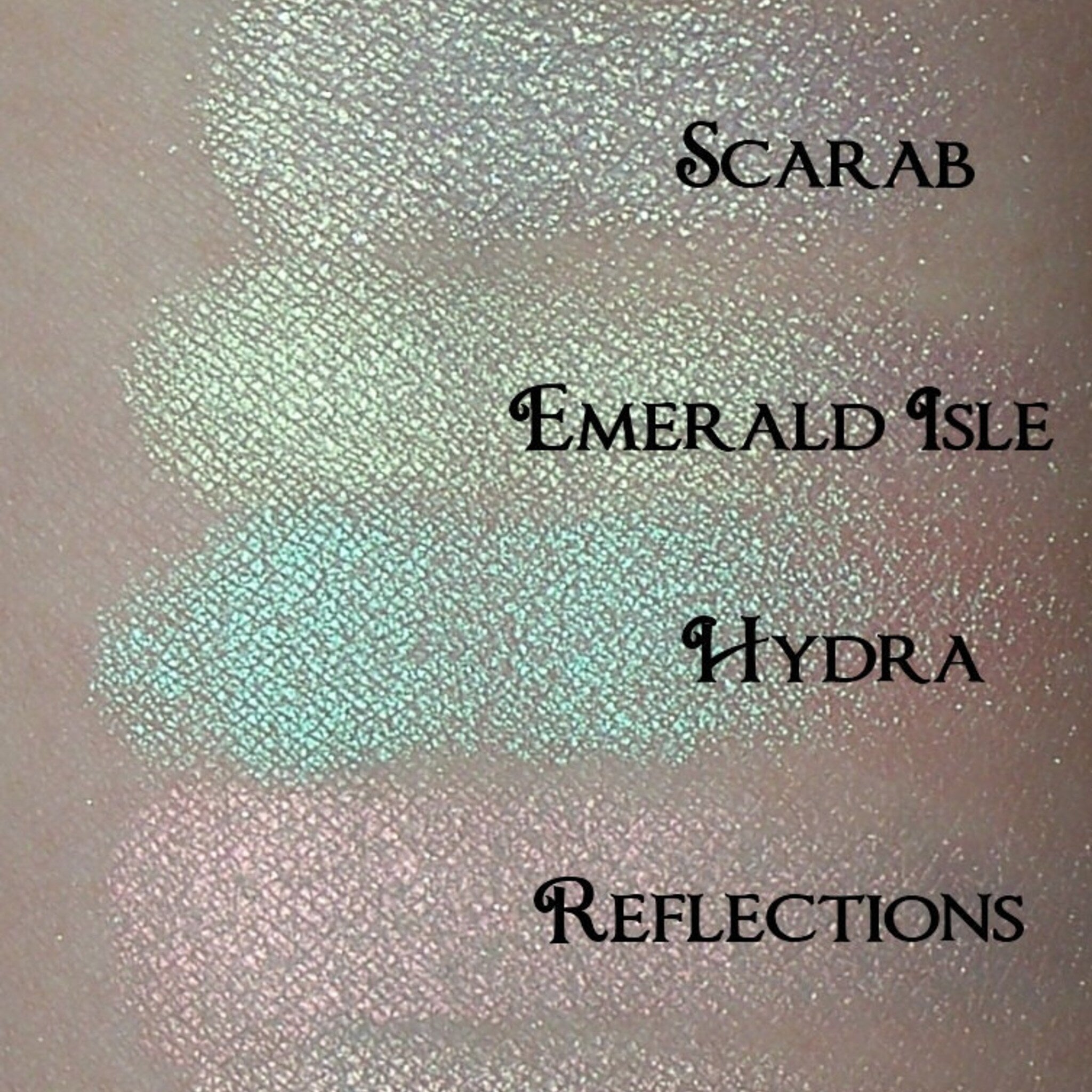 Close-up of six iridescent eyeshadow pans in cool-toned shades with shimmer finish, stacked vertically