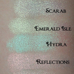 Close-up of six iridescent eyeshadow pans in cool-toned shades with shimmer finish, stacked vertically