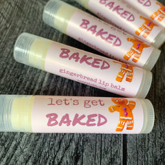 Lip balm tubes with pink labels, gingerbread man graphic, and "BAKED" text, cozy sloth brand