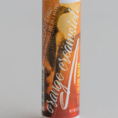 Lip balm tube with orange and white text on orange background, Windrift Hill brand