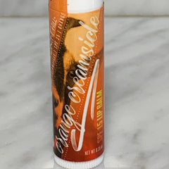 Lip balm tube with orange and white label, "Orange Creamsicle" text, Windrift Hill brand