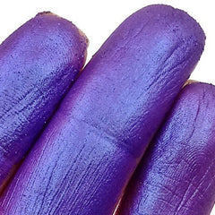 Close-up of fingers applying blurple duochrome eyeshadow with a shimmering color shift effect on eyelid