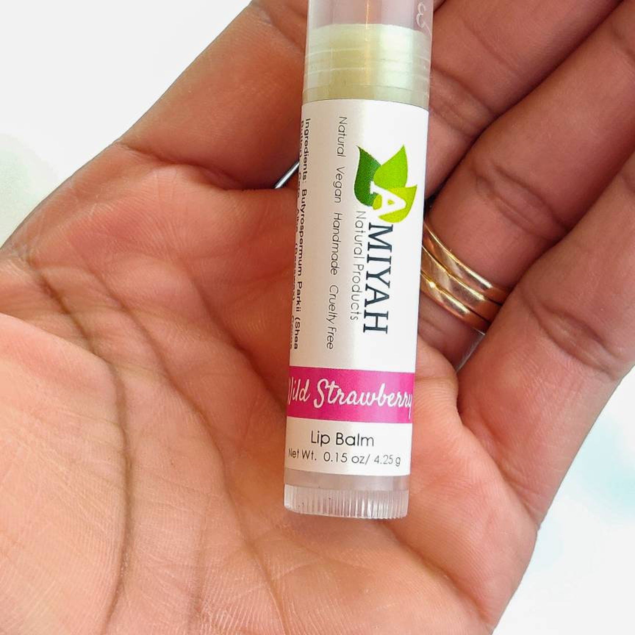 Lip balm tube with white and pink label, held in hand, Amiyah Natural Products brand