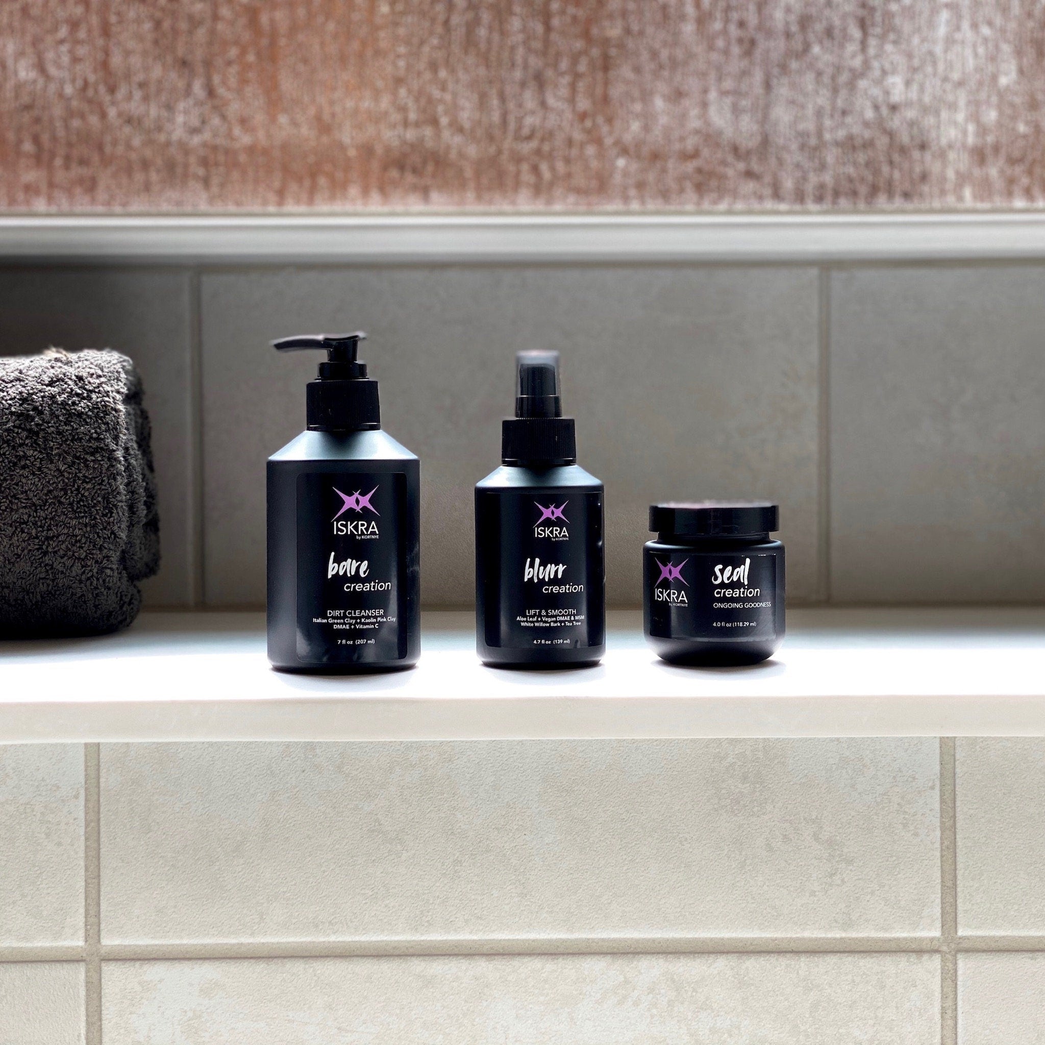 Skincare products with black bottles, white text, and ISKRA logo on a bathroom shelf