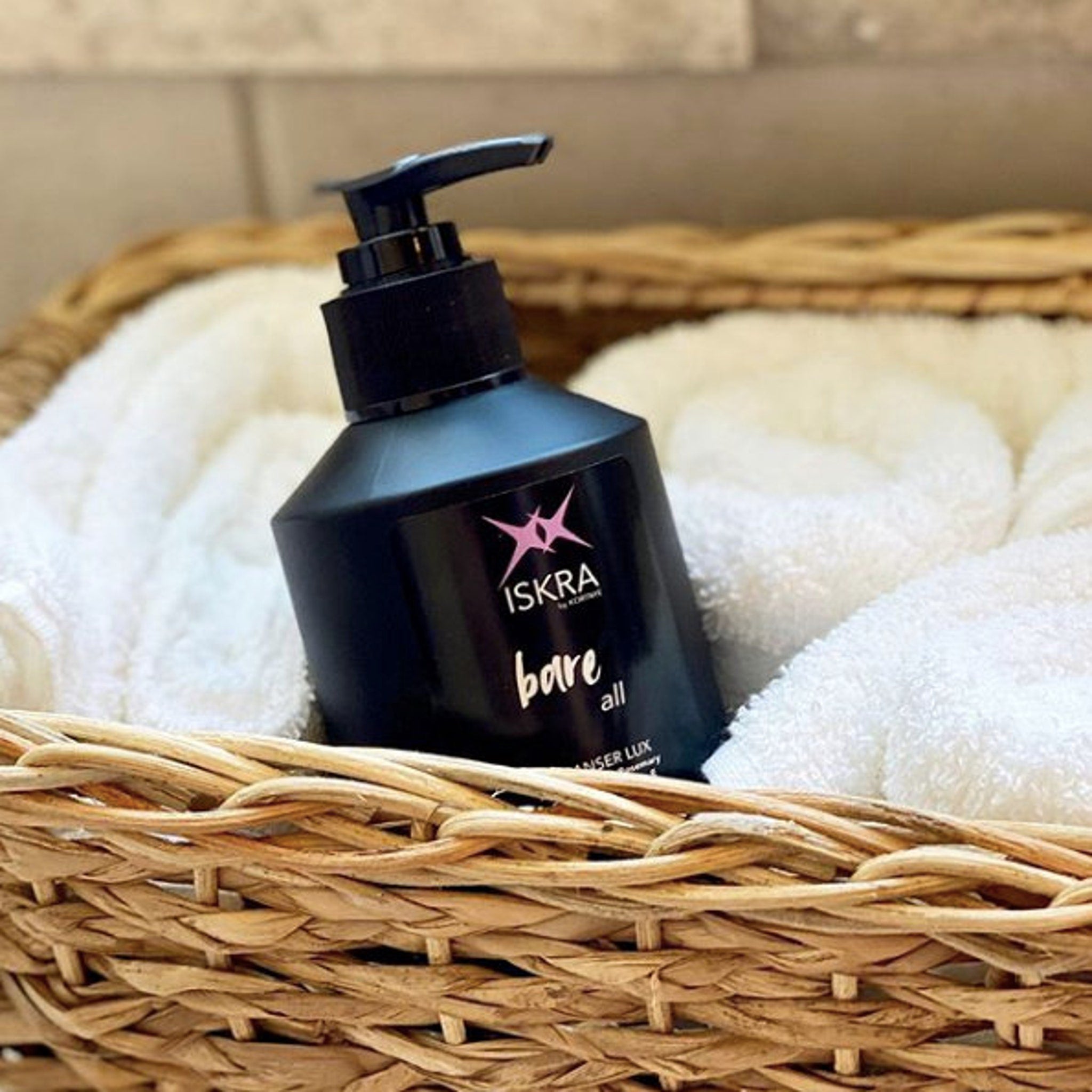 ISKRA bare all black bottle with pump in woven basket with white towels