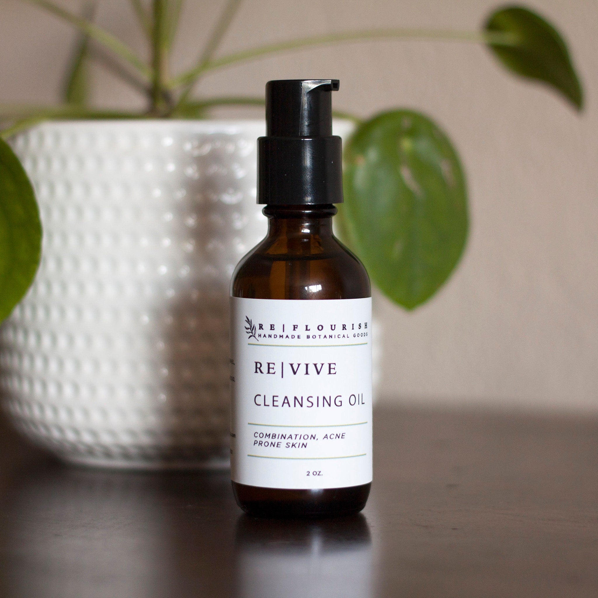 Cleansing oil bottle with brown glass, black pump, and white label with text RE|VIVE