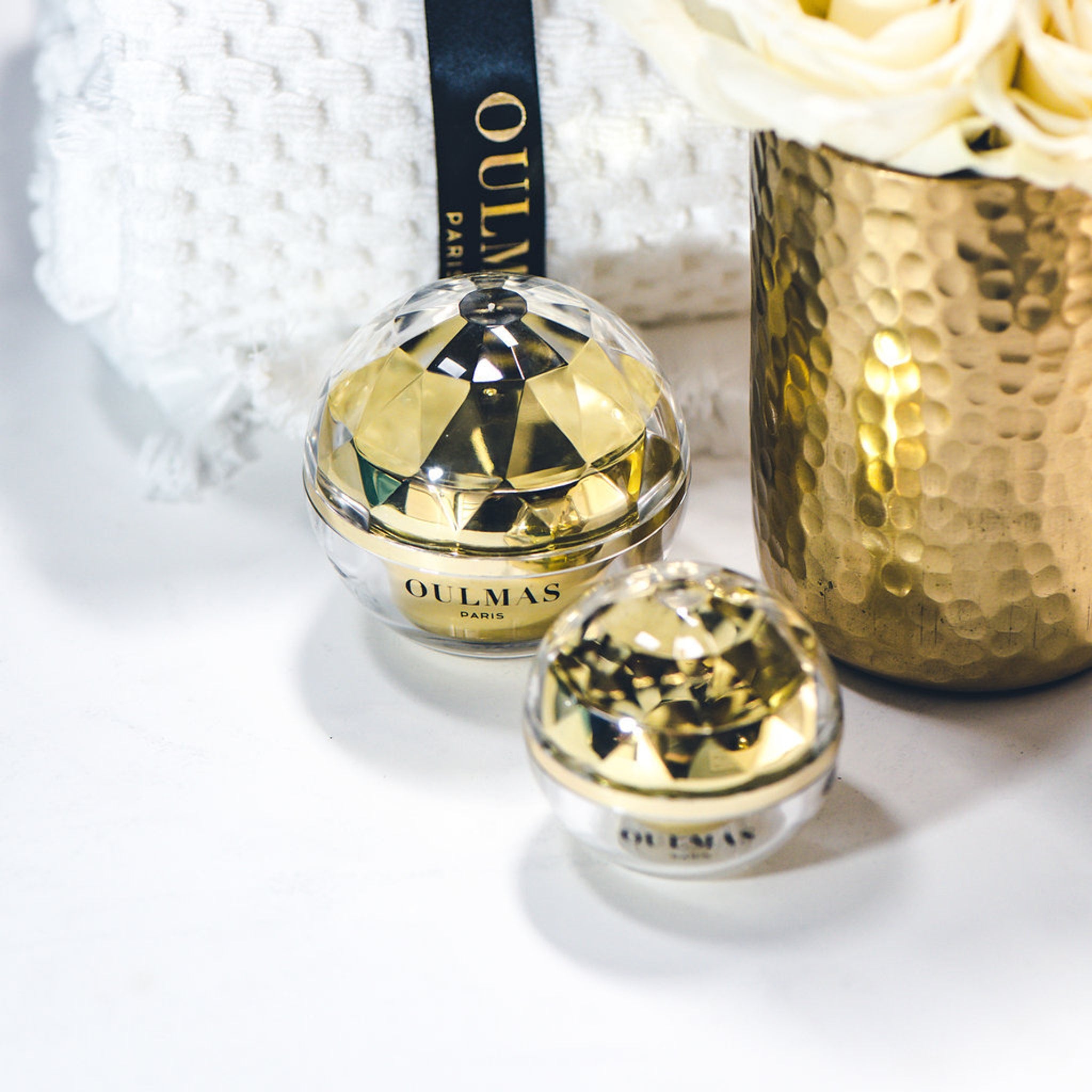 Cosmetic jars with gold and clear faceted design, OULMAS PARIS brand visible, on white surface