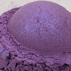 Side view of loose powder eyeshadow jar showing purple and blue duochrome shimmer pigment spilling slightly