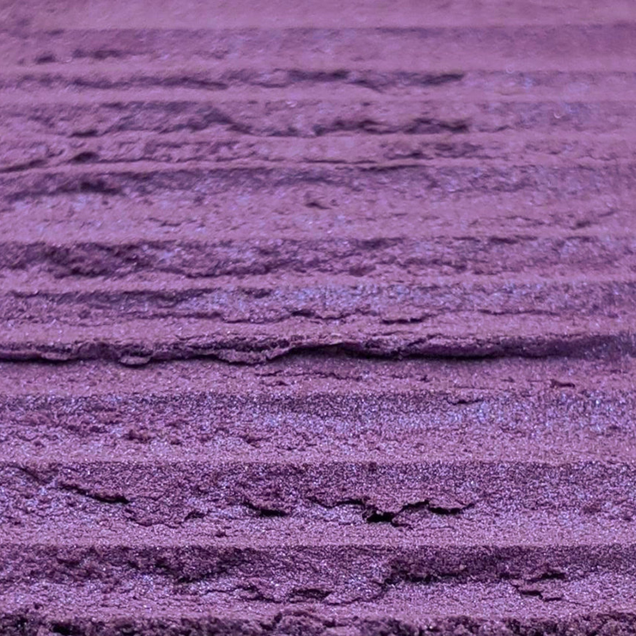 Close-up of fingers applying shimmery purple and blue duochrome loose powder eyeshadow to eyelid