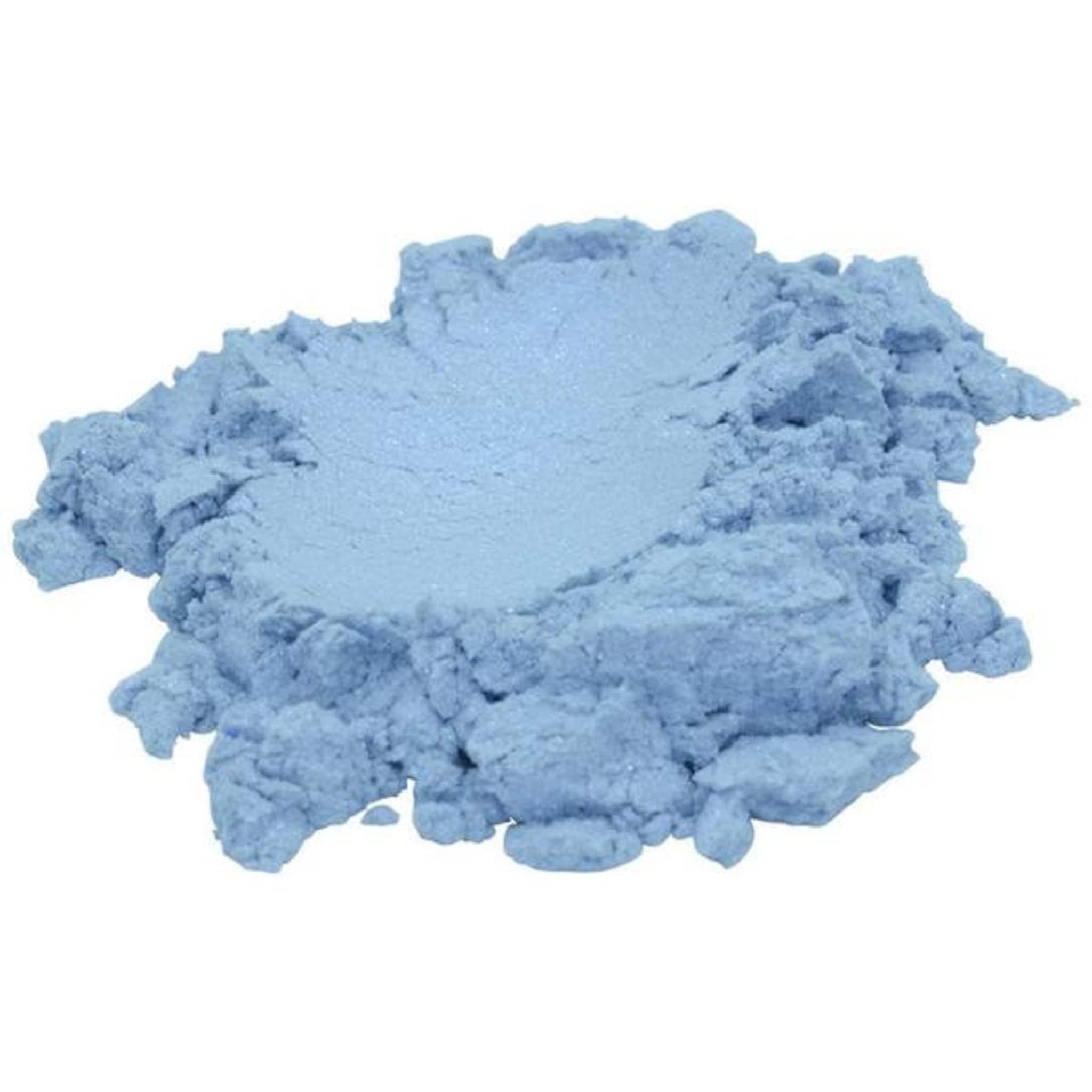 Close-up of vibrant sky blue mica pigment powder shimmering in natural light with bonus travel-size scoop