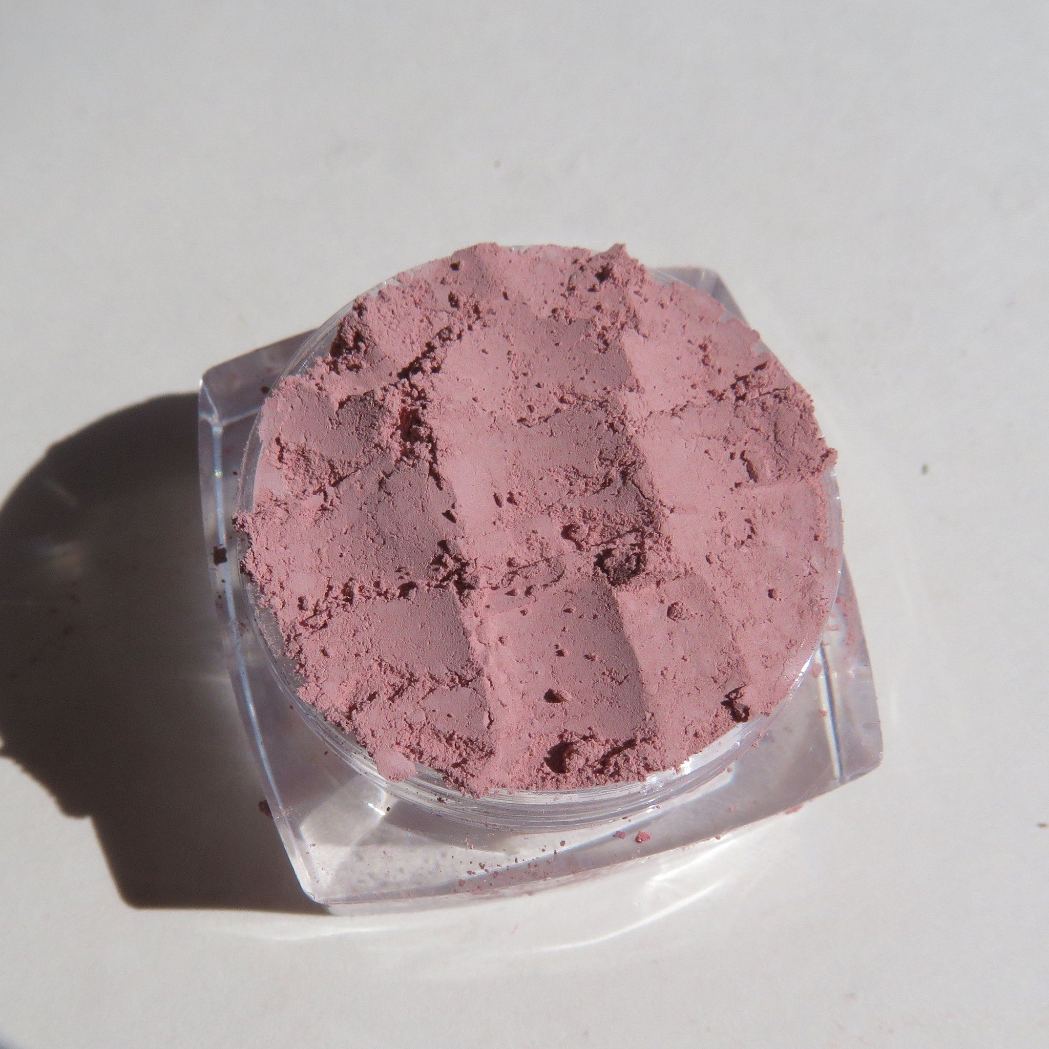 Side view of matte medium pink loose mineral eye shadow in open jar, showcasing powdery texture and vegan label