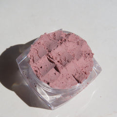 Hand applying matte medium pink vegan eyeshadow with brush, showcasing loose mineral pigment texture