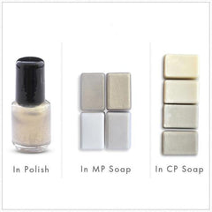 Nail polish bottle with black cap and shimmering gold liquid, plus soap bars of various colors