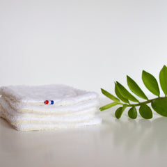 Close-up of double-sided bamboo makeup remover wipe showing textured surface against green leaves