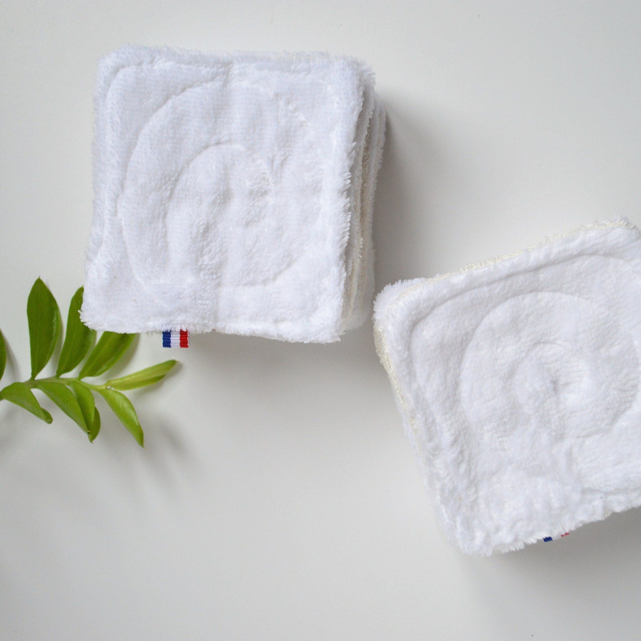 Close-up of double-sided bamboo makeup remover wipe showing textured surface against green foliage backdrop