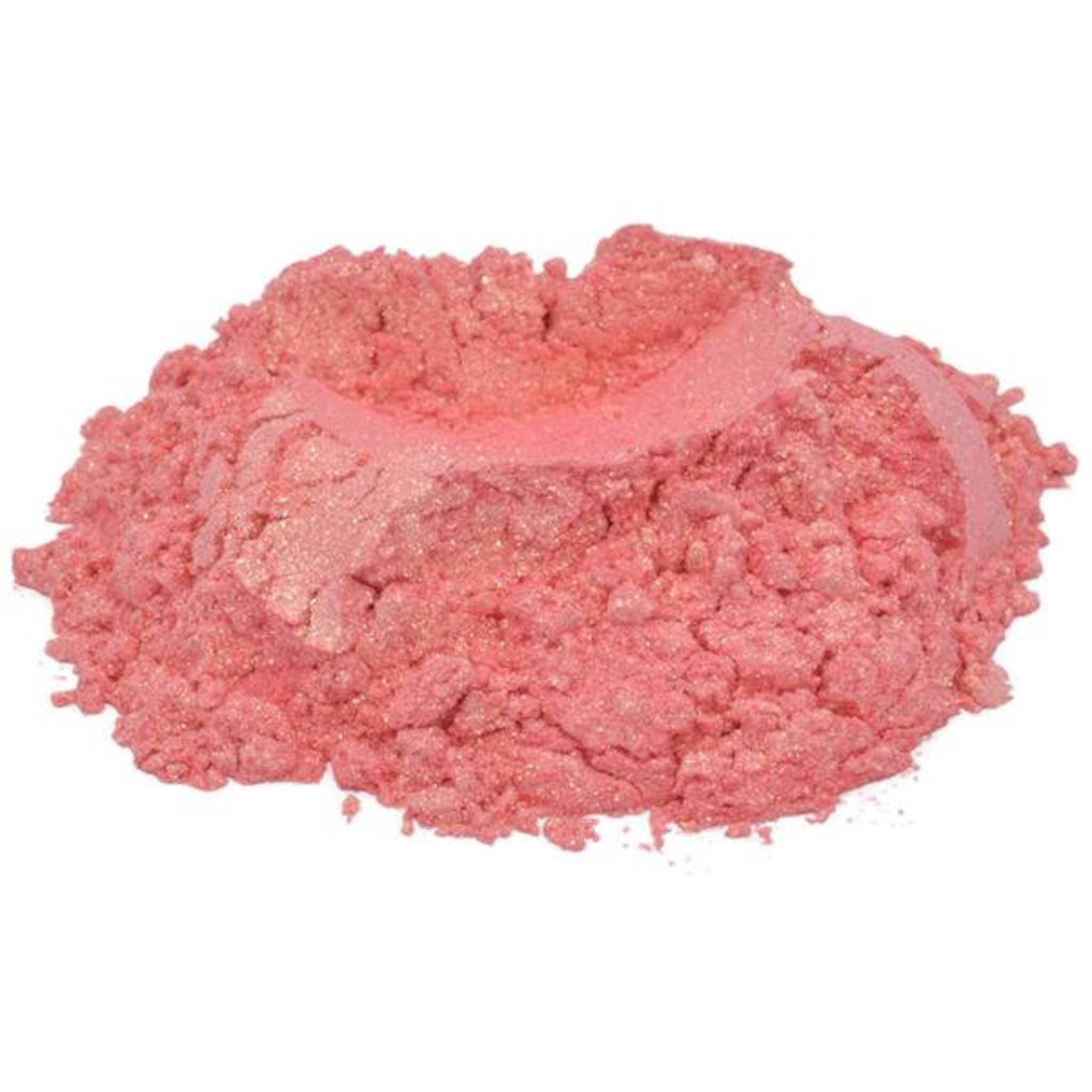 Hand applying coral pink mica pigment powder to eyelid with fingertip for shimmering eye shadow look