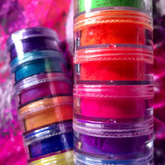 Close-up of shimmery vegan eyeshadow palette showing six vibrant metallic shades in gold, bronze, and jewel tones
