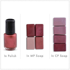 Nail polish bottle with red liquid and black cap next to soap bars in shades of red and pink