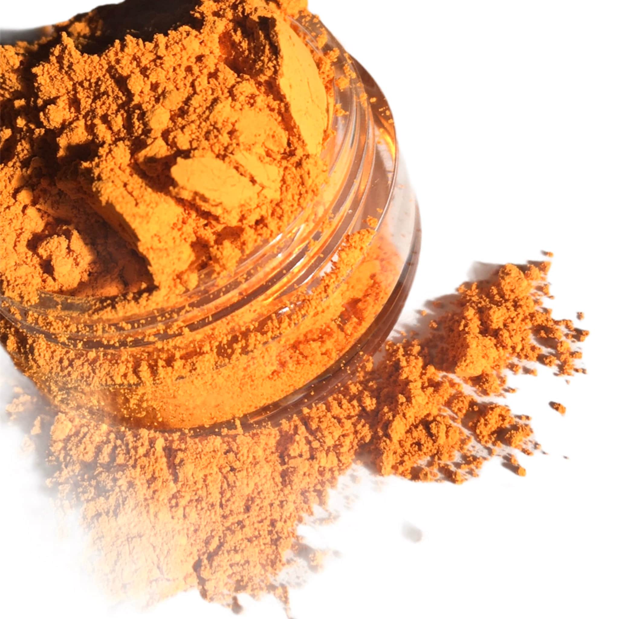 Orange powder spilling from a clear glass jar on a white surface