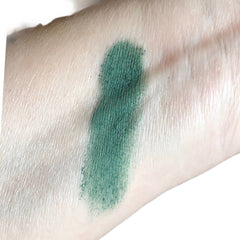 Green eyeshadow swatch on skin, showing textured green pigment on a light skin tone