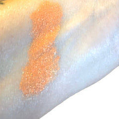 Orange glitter swatch on skin, showing color and texture