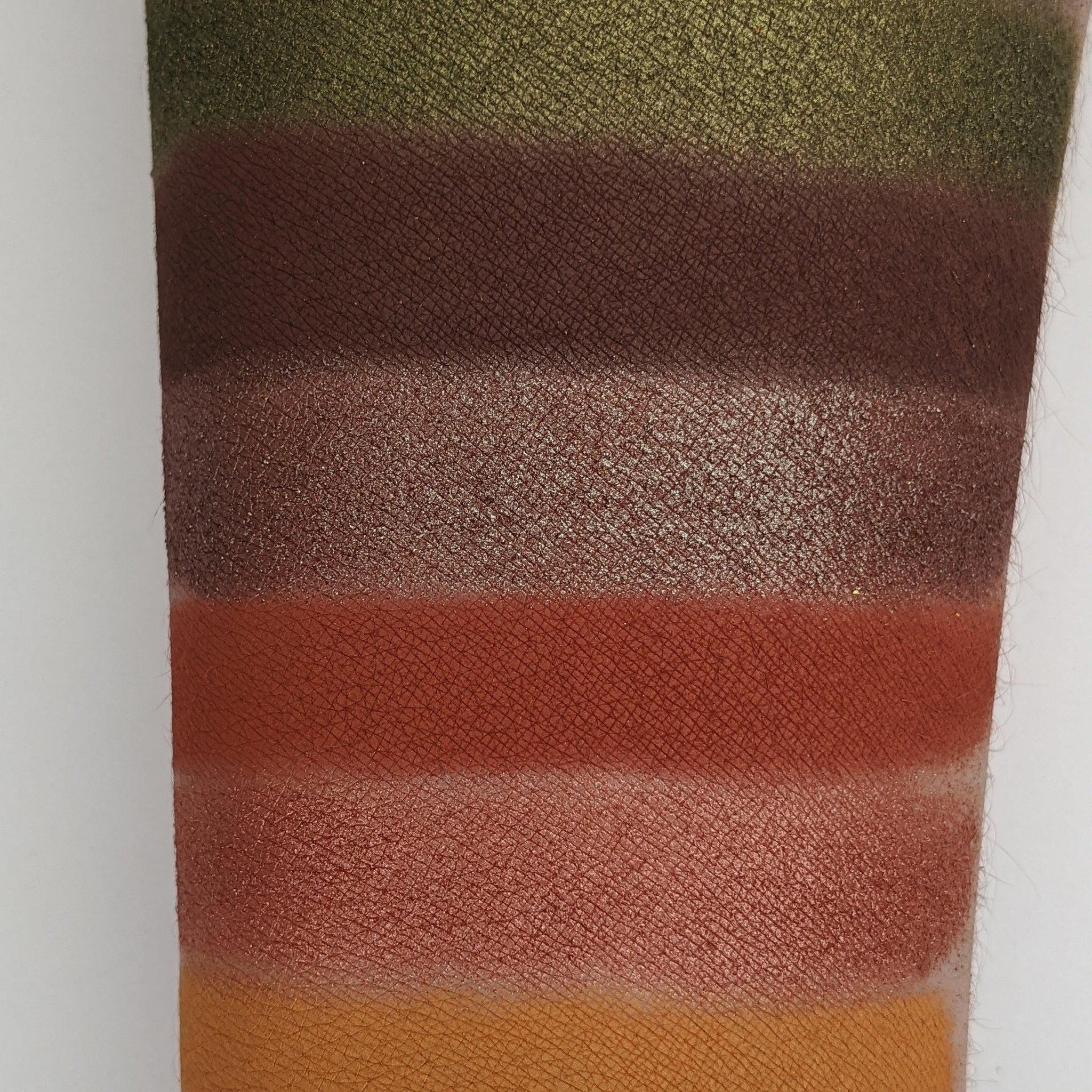 Close-up of Autumn Splendor palette showing matte orange and shimmery brown eyeshadow pans with autumn leaf design
