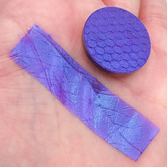 Side view of duochrome blurple eyeshadow pan catching light, showing color shift from purple to blue