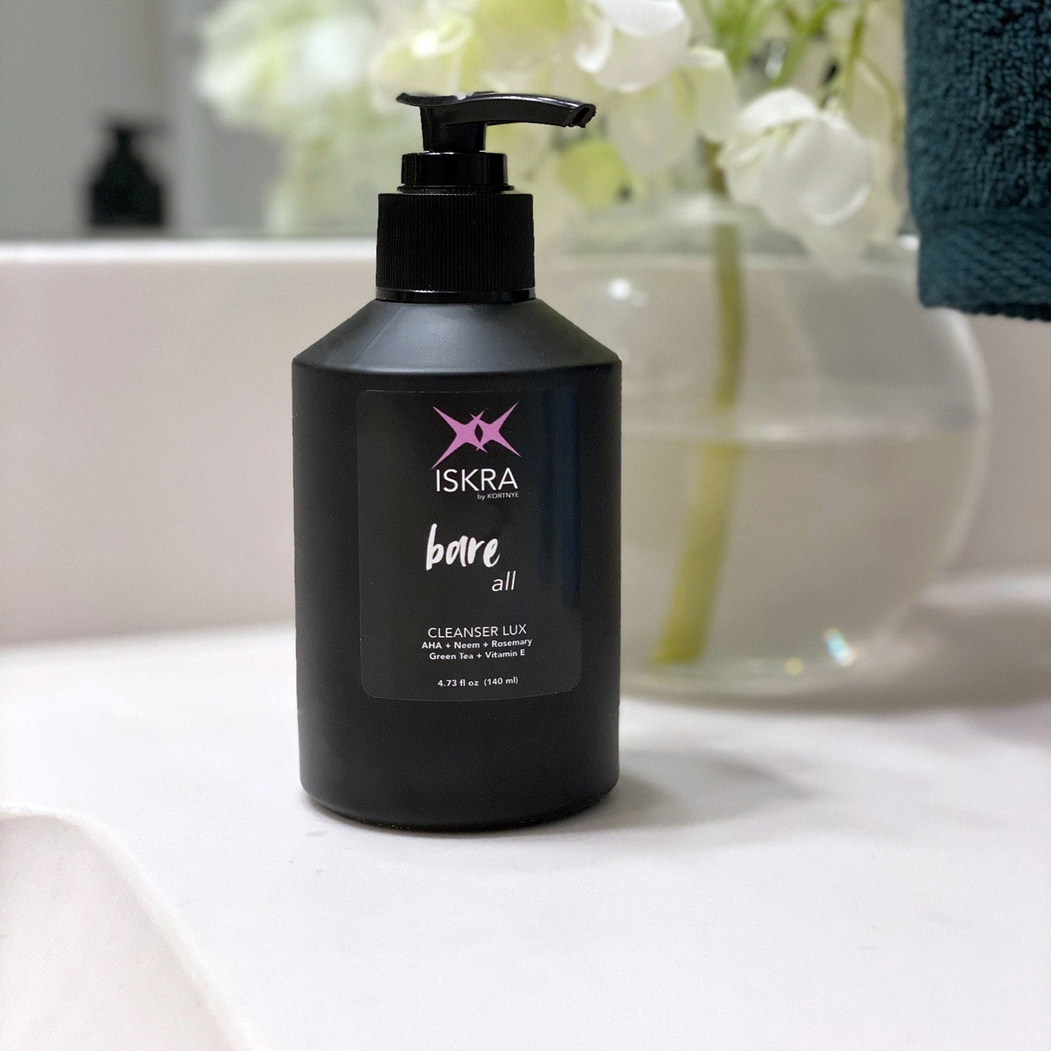Cleanser bottle with black pump, black label, and ISKRA text on bathroom counter