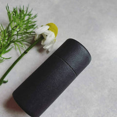 Lip balm black paper tube with white flower and green stem on white background