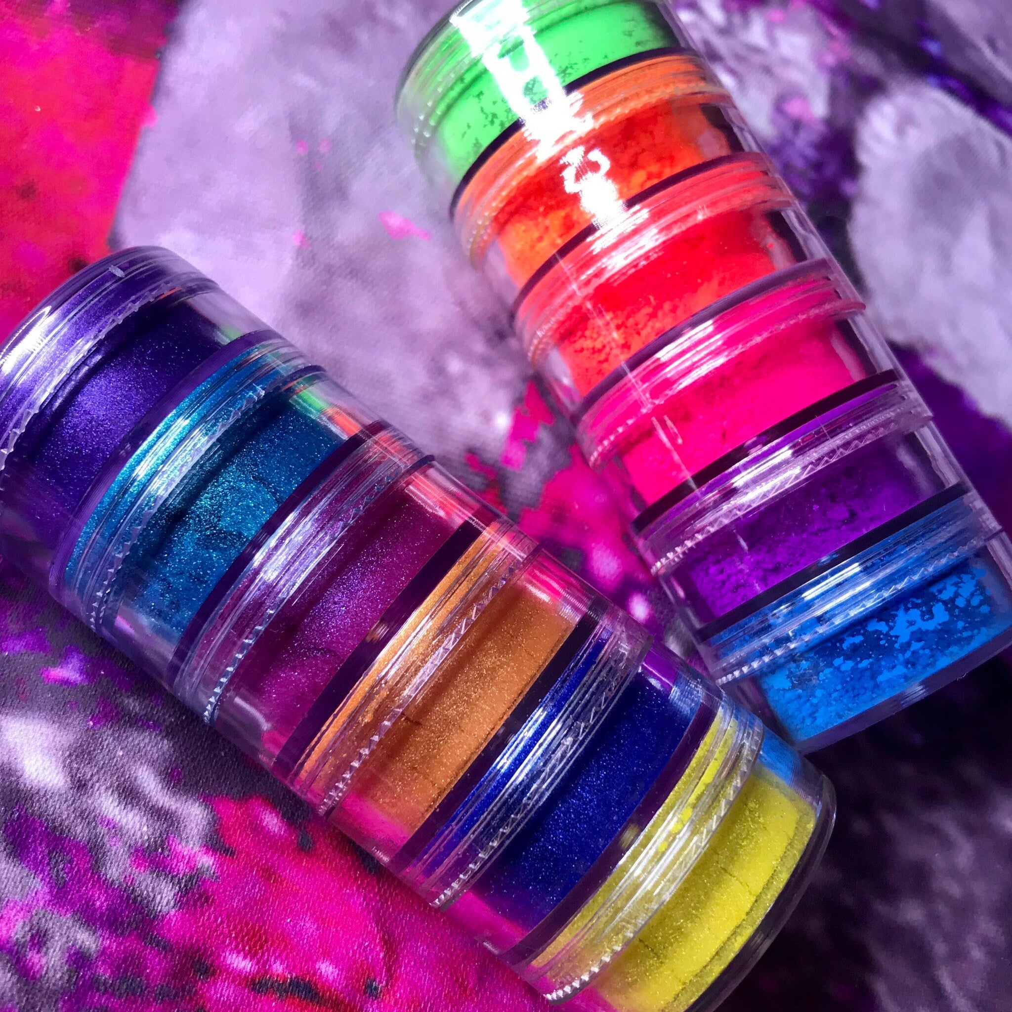 Side view of 12 vegan mineral eyeshadows in matte and shimmery shades arranged in two stacked rows